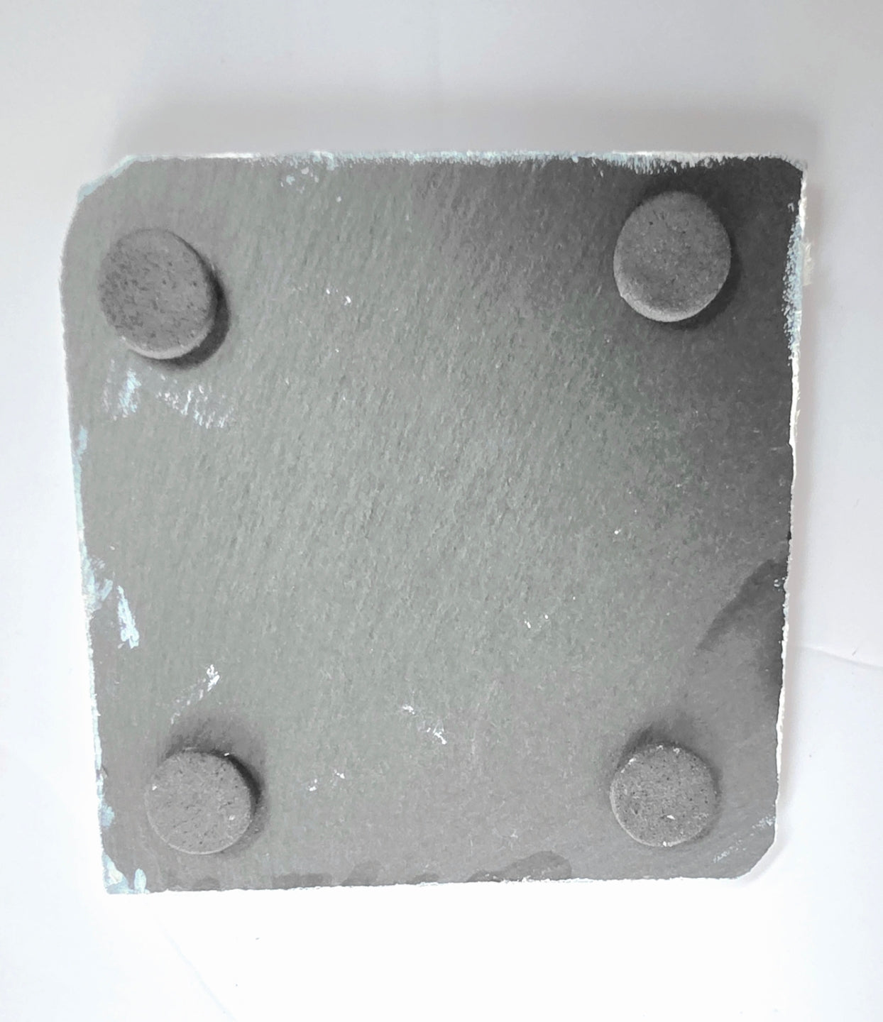 underside of a square slate coaster showing the four protective pads