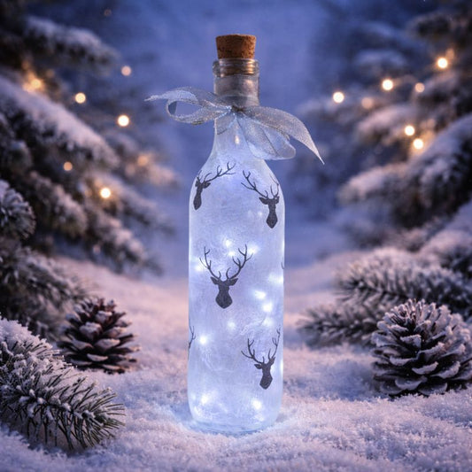 Decorative bottle with LED lights and stags head silhouettes in a snowy forest setting