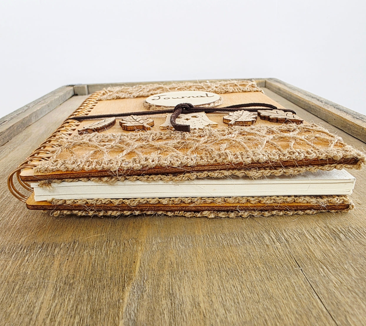 Handmade wooden notebook with burlap decoration on the top and bottom cover. Shown end side on