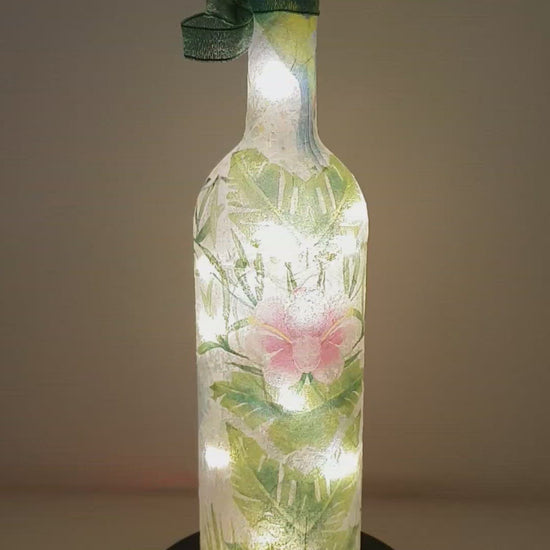 Rotating example of a Lit up bottle with blue Hummingbird detail , pink flowers and green leaves LED cork lights and green bow