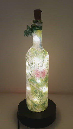 Rotating example of a Lit up bottle with blue Hummingbird detail , pink flowers and green leaves LED cork lights and green bow