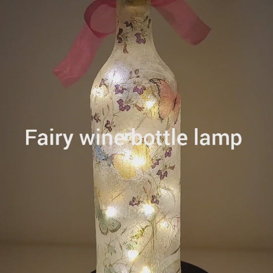 Rotating example of a Lit up wine bottle with Fairy and flower design. Pink bow.