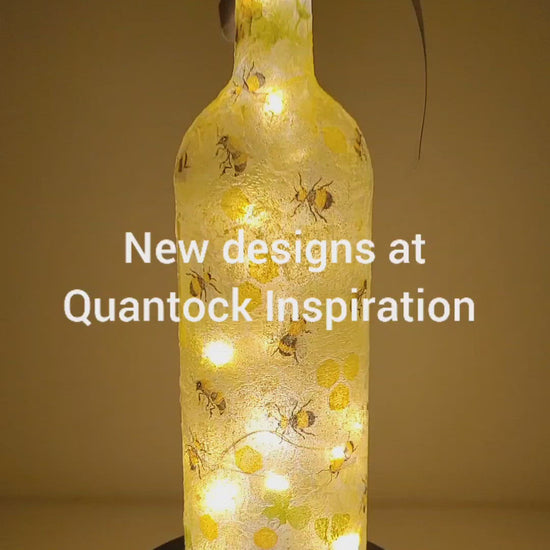 Rotating example of a lit up wine bottle with bumble bee detail. cork LED lights and grey bow