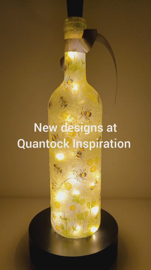 Rotating example of a lit up wine bottle with bumble bee detail. cork LED lights and grey bow