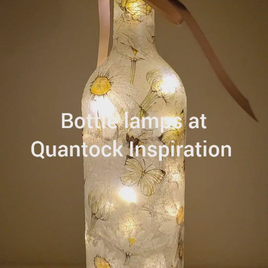 Rotating example of a Lit up bottle with Bumble bees and daisies detail. Cork LED lights, Rose gold coloured bow
