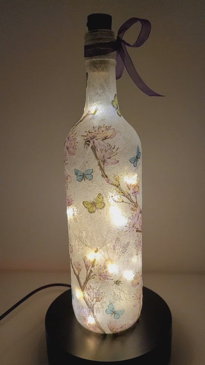 Rotating lit up wine bottle with flower and butterfly detail. Purple bow 